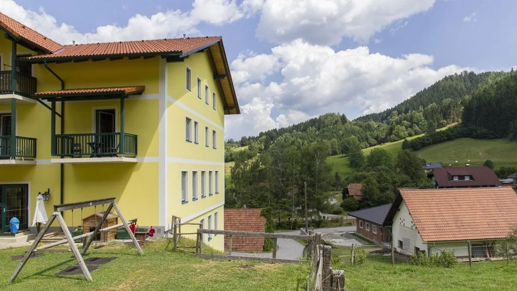 Der Landgasthof Sepplwirt mit Spielplatz vor bewaldeten Hügeln